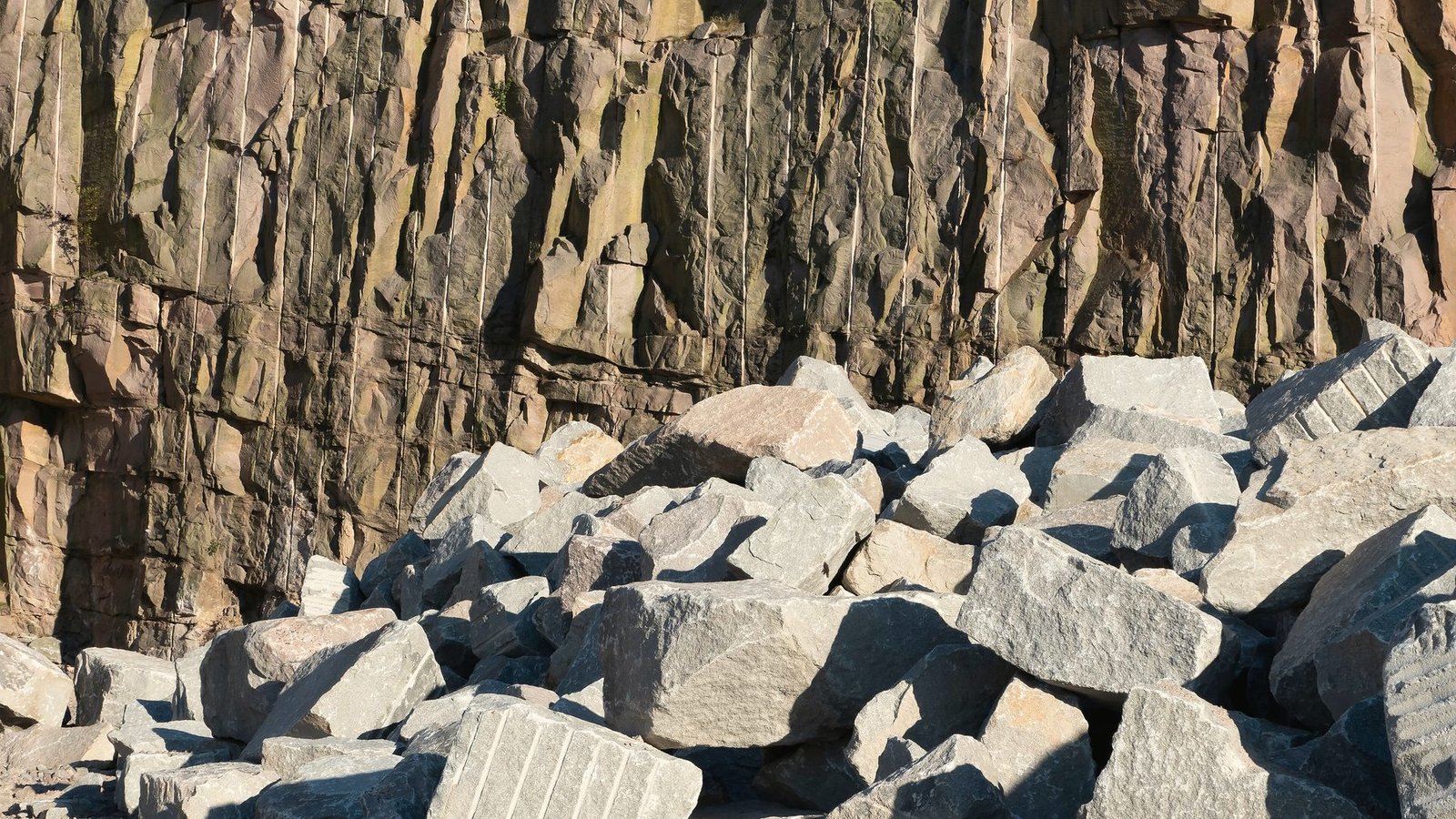 Broken granite blocks piled at the foot of a quarry face